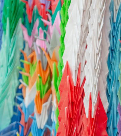 Photograph of strands of colorful paper cranes.