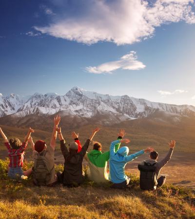 distant rear view of women with arms uplifted on mountain outing