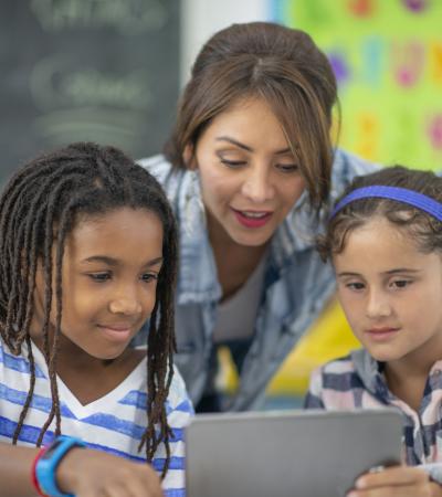 female teacher assisting two girls with technology education