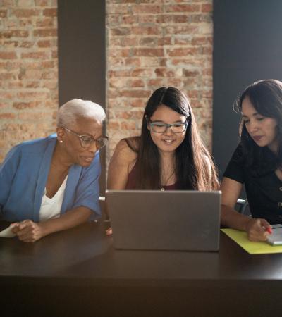 Three people of varying ages looking at a laptop screen