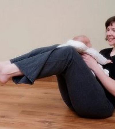 Woman holding baby in boat pose