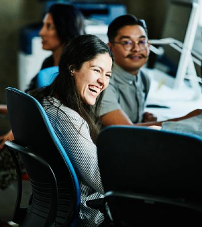 A woman sitting at a conference table, smiling and laughing with other people