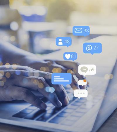 Photo of hands typing on laptop with various media icons