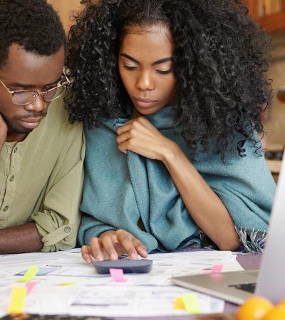 Photo of two people looking at financial papers with a calculator. 