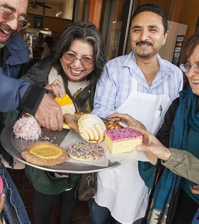 People gathered around a tray of pastries