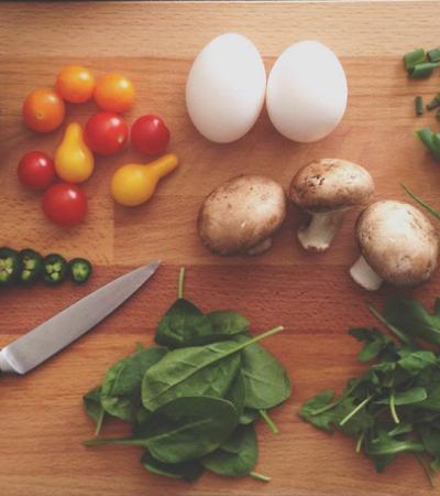 cutting board with vegetables being cut up with a knife