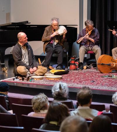 A band sitting on the stage floor performing