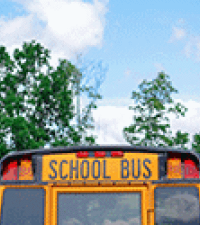 Back end of a school bus set against some trees and sky