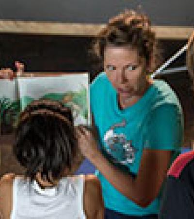 Woman reading a book aloud to a group of children