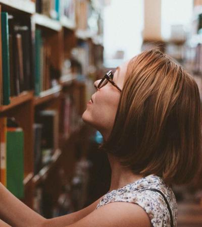 A woman looks for a book in the stacks. 