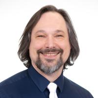 man with beard smiling at camera in button up shirt and tie