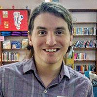 Austin Jenkins smiling toward camera in library