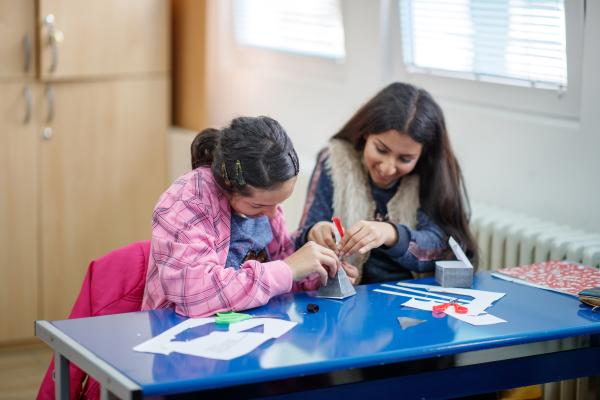 Photograph of two young people working together to create a paper pyramid.