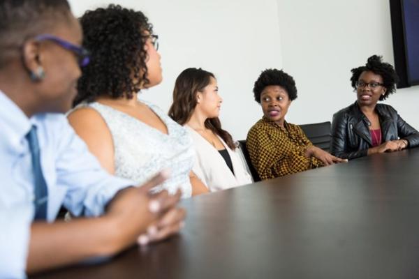 Five people sitting around a table participating in conversation.