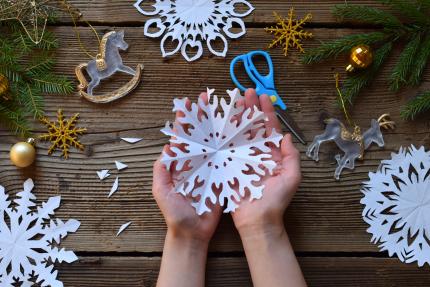 making paper snowflakes with your own hands to spread holiday joy