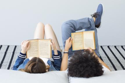 two young people reclining on pillows and reading books