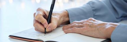 hands of elderly woman writing in a notebook