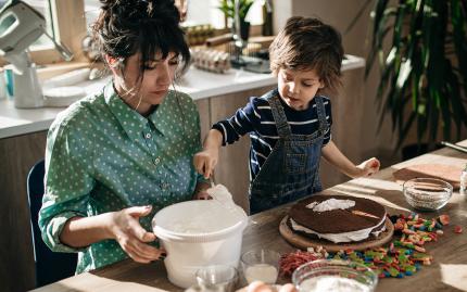 Photo of mother and child decorating a cake.