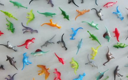 Photograph of small multi-colored dinosaur toys.