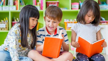 Three children sitting down and looking at books