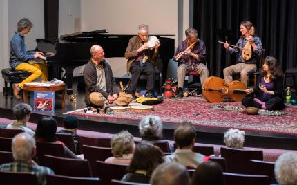 A band sitting on the stage floor performing