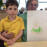 A senior poses with a child artist and their finished portrait