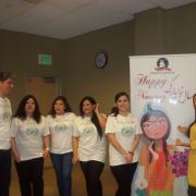 Nowruz Celebration volunteers pose next to banner