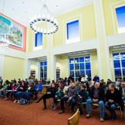 Large library room full of people attending Traveling Stanzas opening reception