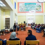 Large library room full of people attending Traveling Stanzas opening reception