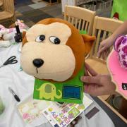 Photograph of finished stuffed animal taxidermy board. Monkey head on a green board with an elephant illustration and the name Gordie written bellow.