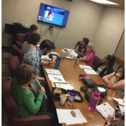 Photograph of participants sitting around a table with notebooks open.