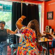 Photograph of three people celebrating a trivia win with their arms up in the air