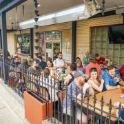 Photograph of people sitting at tables outside of a brewery