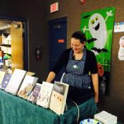 Woman standing behind a table with a book display