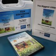 Photograph of a Film Discussion Kit for "The Biggest Little Farm." Photograph shows the DVD, Film Discussion Guide binder, and container.