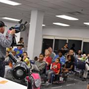 Man holds telescope and speaks to an audience