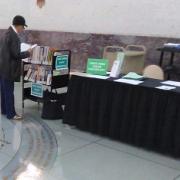 A woman reads a book while standing next to the greeting table.