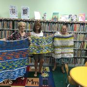 Three women holding up mats