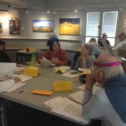 The students talk to one another while seated around a table.