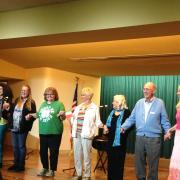 The participants finish performing their memoirs and stand on stage holding hands.