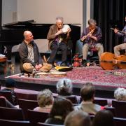 A band sitting on the stage floor performing