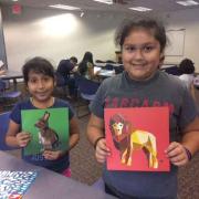 Two girls show their paint by sticker images. 