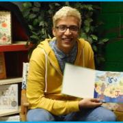 Student poses with his illustrated storybook