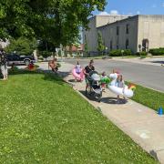 Photograph shows children outside playing a sidewalk chalk game with pool floaties on.