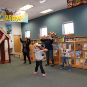 An instructor leads a group of children and their guardians through Zumba dance moves.