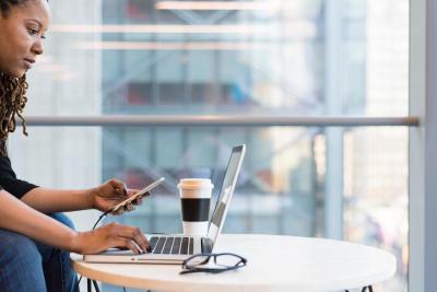 Woman looking at laptop and cell phone