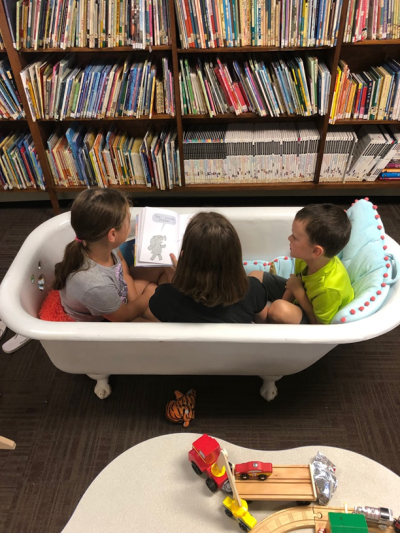 Three children reading in a bathtub