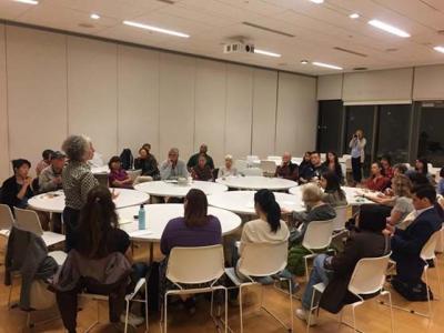 group of people sit at tables in conference room