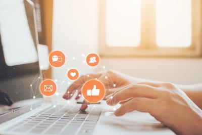 Photo of hands typing on laptop with various marketing icons 