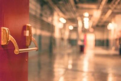 A red door opening inward to show a blurry hallway.